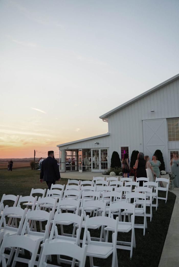 Outdoor sunset wedding venue with white chairs