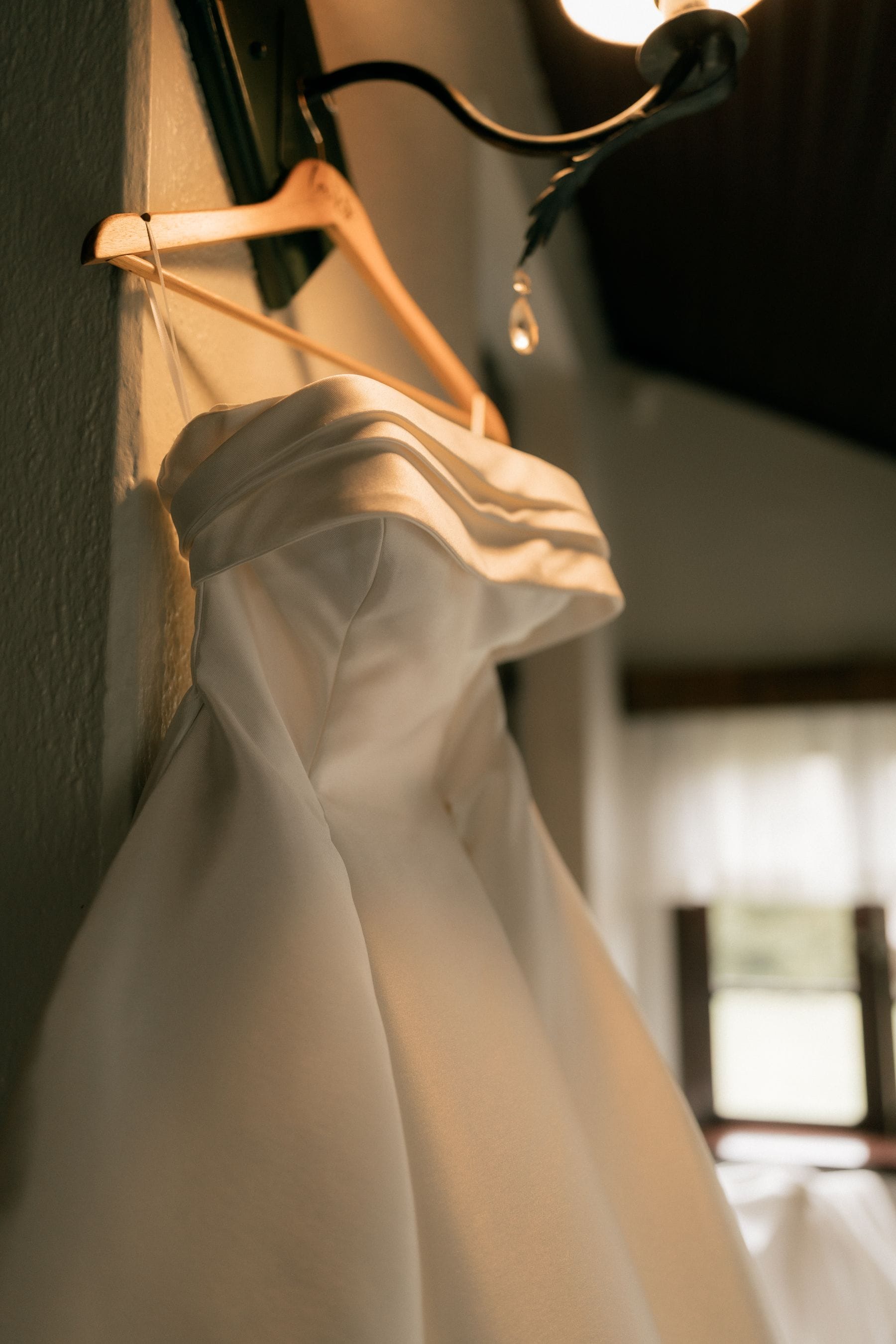 A wedding dress hanging in soft natural light