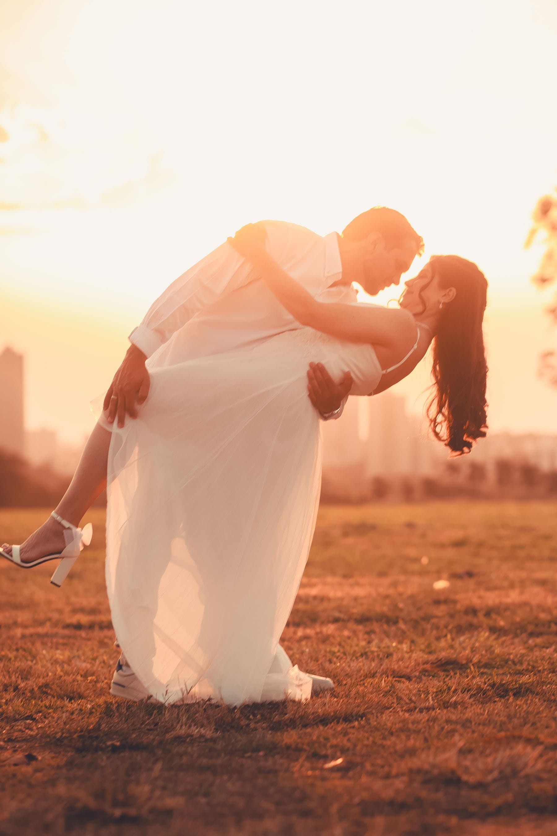 A couple embracing in a field at sunset